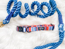 Load image into Gallery viewer, Showcaing flat lay Red, Blue and White stripped pattern Dog Collar with metal D ring in black colour from Woof First. The Collar is sitting on navy blue leash