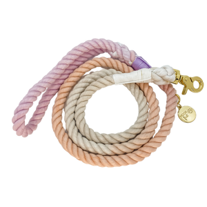 The image shown is of the Dogs Rope leash in 3 blended colours of grey, pink and purple. The rope leash has gold metal hardware finishes and has Woof First imprinted on a round charm.