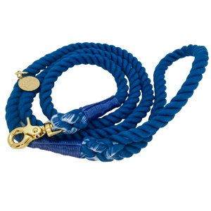 The image shown is of the Dogs Rope Leash in Dark Blue colour. The rope leash has gold metal hardware finishes and has Woof First imprinted on a round charm.